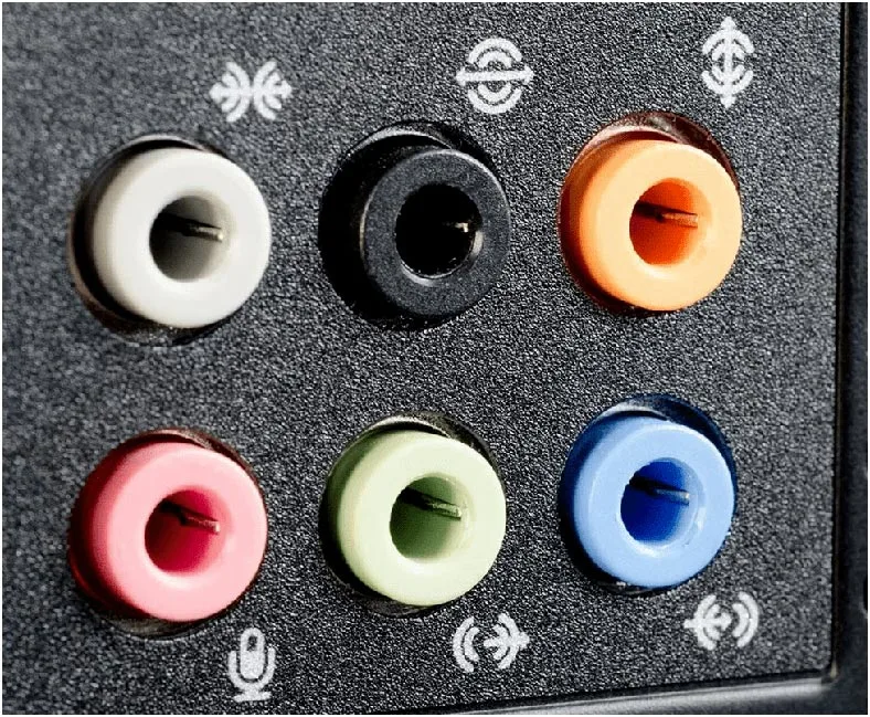 Close-up of a 3.5mm TRRS microphone plug being inserted into a pink microphone jack on a desktop PC rear panel